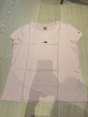 Ljusrosa T-shirt från Tommy Hilfiger - Ljusrosa T-shirt från Tommy Hilfiger med broderad logga. Klassisk rund halsringning och korta ärmar. Tillverkad i mjuk bomull för en bekväm känsla.