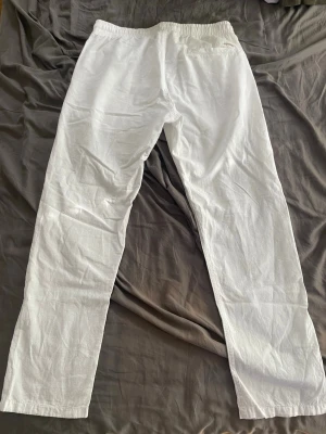 Vita linnebyxor från Jack&Jones - Säljer ett par vita linnebyxor med rak passform och resår i midjan. Byxorna har sidofickor och är tillverkade i ett lätt och luftigt linnematerial som är perfekt för varma dagar. Stilrena och enkla att matcha med olika outfits.