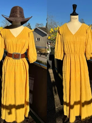 Gul maxiklänning 💛 - Gul ny maxiklänning med v-ringning & puffärmar. Resår i midjan & ett strukturerat tyg. Axelbanden har små volangdetaljer. Trekvartsärm. Lägg till ett bälte + hatt & ändra stilen till 🤠 💛