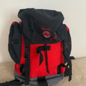 Nevada Climber - Säljer en rymlig röd och svart ryggsäck från Nevada Climber. Väskan har flera fack, justerbara axelremmar och smarta spännen framtill. Perfekt för dig som gillar äventyr och vill ha en cool och praktisk väska med plats för allt du behöver.