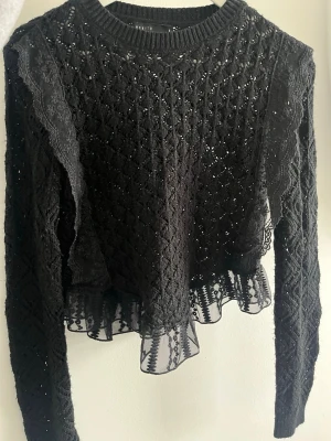  Spetsatickad tröja Mohito  - Säljer en svart stickad tröja med spetsdetaljer och volang längst ner från MOHITO. Använd några gånger men fortfarande fint skick!🖤 