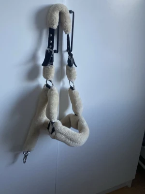 Fårskinnspaddad grimma till häst - Säljer en beige grimma till häst med mjuk fårskinnspaddning och svarta detaljer i läder. Grimman har metallspännen och är designad för att vara extra bekväm för hästen. Perfekt för dig som vill ha något mjukt och stilrent till stallet.