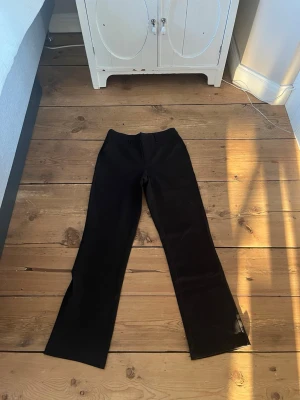 Svarta utsvängda byxor - Svarta byxor med utsvängda ben och hög midja. Snygg och enkel design som passar till många olika stilar. Materialet ser ut att vara stretchigt och bekvämt, perfekt för dig som gillar en stilren look.