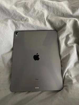 Apple iPad Pro 12.9 tum grå - Säljer en Apple iPad Pro 12.9 tum i rymdgrå färg. Surfplattan har en stor skärm med tunna kanter och baksida i aluminium. Perfekt för både studier, kreativt arbete och underhållning. Snygg och modern design med Apples logga på baksidan. Och tyvärr en spricka på bakkameran men funkar fortfarande som normalt