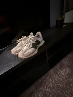 New Balance beige och gröna sneakers - Säljer ett par snygga New Balance sneakers i beige mocka och textil med gröna detaljer och klassisk N-logga på sidan. Skorna har en låg silhuett och gummisula med mönstrad undersida för bra grepp. Perfekta för dig som gillar stilrena och sportiga sneakers.