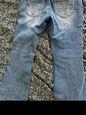 Blå flared jeans - Säljer ett par blå flare jeans med snygga bakfickor och dekorativa sömmar. Storlek L, men etiketten är bort klippt. Använd några gånger, så dem är i princip nya. Omklippt och sydd för att passa runt 160cm.
