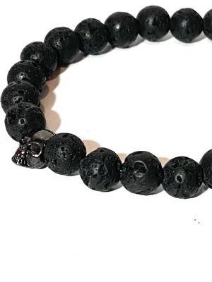 Armband med svarta ädelsten pärlor  - Armband svarta ädelsten pärlor lava rock med en döskalle länk i mitten.  Längd 18cm bredd 8mm