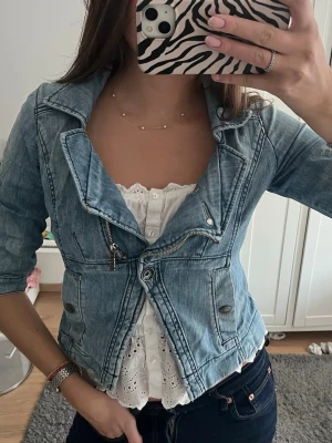 Ljusblå kort jeansjacka med dragkedja - Säljer en ljusblå jeansjacka med cool asymmetrisk dragkedja och detaljerade sömmar. Jackan har trekvartärmat. Den är i storlek L men skulle säga att den mer är en M/S. Perfekt för att lyfta vilken outfit som helst med en avslappnad men trendig vibe.💝🌷