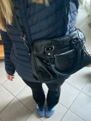 Svart väska, citybag inspirerad - Kan sänka pris! Säljer en rymlig svart axelväska med både handtag och lång axelrem.💞💞Bra skick, bara små slitage som ger en cool effekt. Väskan har metalldetaljer och rimlig insida. 💕💕 