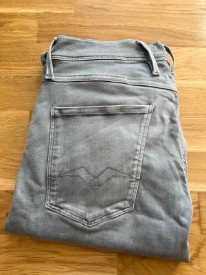 Ljusgrå slim fit jeans - Säljer ett par ljusgrå slim fit jeans med klassisk femficksdesign och bälteshällor. Jeansen har en diskret söm på bakfickan och är tillverkade i ett mjukt denimtyg med stretch för extra komfort. Perfekta för en avslappnad och lite varmare look. Skickas snabbt och hör av er vid minsta funderingar!!