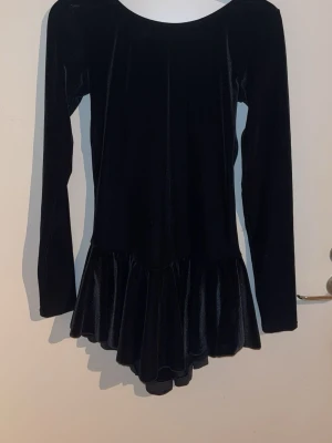 Konståkningsklänning  - Svart konståkningsklänning i mjuk sammet med lång ärm och utsvängd kjol. Inbyggda trosor.  Använd några gånger men är i gott skick