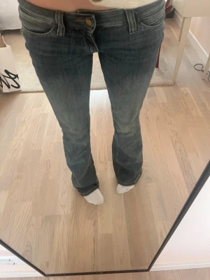Weekday jeans blå - Säljer ett par blå bootcut jeans med låg midja och klassisk femficksdesign. Jeansen har en lätt tvättad look och sitter tajt över låren för att sedan bli vidare nedtill. Perfekta för dig som gillar en avslappnad men trendig stil. 27/32