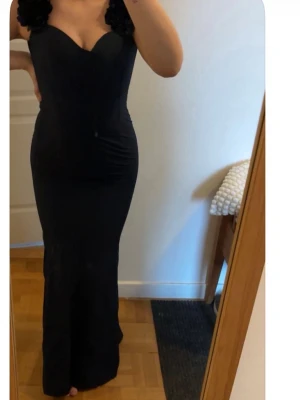 Marinblå långklänning - balklänning  -  Marinblå långklänning med figurnära passform och volangdetaljer på axelbanden.  Perfekt som balklänning eller en klänning vid exklusiva tillfällen. Storlek Xs. Prislapp kvar aldrig använt