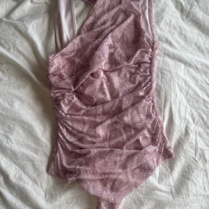 Rosa boddy med ormmönster - Trendig rosa boddy med ett snyggt ormmönster och draperade detaljer framtill. Asymmetrisk axelband ger en cool look 