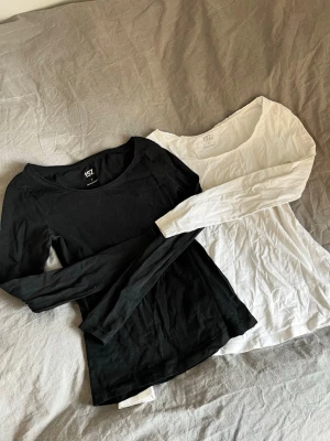 Svart och vit långärmad topp 157 - Två basic långärmade toppar från 157, en svart och en vit. Båda har rund halsringning och är tillverkade i mjuk bomull som känns skön mot huden. Perfekta att styla lager på lager eller bära som de är.