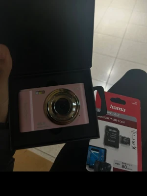 Rosa digitalkamera  - Säljer en snygg rosa digitalkamera med rund lins och metallic-detaljer. Kameran är kompakt och smidig att ta med sig. Den kommer med laddare sd kort och jag her även minneskort som du kan smidigt föra över bilderna till din mobil. För att föra över bilderna kommer du behöva en kamera adapter 💜🌸