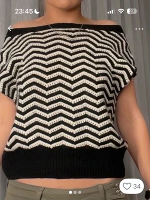 Svartvit offshoulder topp - Säljer en svartvit offshoulder topp med zigzag-mönster. Toppen är stickad och har en bred resår vid midjan för en snygg passform. Perfekt för dig som gillar en unik och trendig stil.
