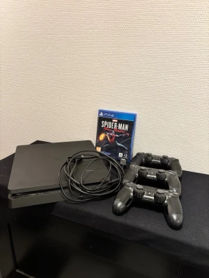 PlayStation 4 Slim med tre kontroller - Säljer mitt svarta PlayStation 4 Slim pga att jag skaffat mig ett PS5 och nu samlar denna konsol bara damm. Du får en helt ny HDMI kabel och strömkabel och 3 kontroller. Kontrollerna har sina egna få skavanker men funkar bara bra när man använder dem. Du får även med ett Spiderman Miles Morales som har ett värde på ish 500kr. Tveka inte på att höra av er vid köp eller frågor! 