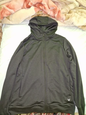 Svart hoodie från SOC med dragkedja - Säljer en svart hoodie från SOC i storlek L. Hoodien har hel dragkedja framtill, två sidofickor och en justerbar huva. Tillverkad i ett tekniskt funktionsmaterial som andas och känns lätt mot kroppen. Perfekt för träning eller chill.