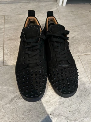 Svarta skor loubs - Tjena säljer ett par riktigt feta loubs.De är lite slitna här och där men kanske inget man ser när du går runt med de.Har sytt de där bak för skon gick upp där.Båda skona saknar varsin knapp vid sidan se på bilderna.Alla spikar är kvar.Vet inte om äkthet där säljer så billigt