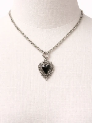 Silverfärgat halsband med svart hjärthänge - Unikt halsband i silverfärg med en grov kedja och ett detaljerat hänge i form av ett svart hjärta omgivet av dekorativa mönster. Hänget har en vintageinspirerad look med små pärlliknande detaljer runt hjärtat. Perfekt för dig som gillar statement-smycken.