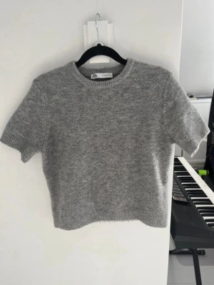 Grå stickad kortärmad tröja från ZARA - En grå kortärmad stickad från zara. Storlek M men är väldigt liten i storlek så passa mer XS. Den har lite ytludd men annars mycket bra skick.