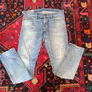 Ljusblå Ralph Lauren jeansbyxor - Säljer ett par sköna ljusblå jeansbyxor från RL med slitningar som design. Byxorna är i bra kvalitet. Hör av er vid funderingar.(34/34)