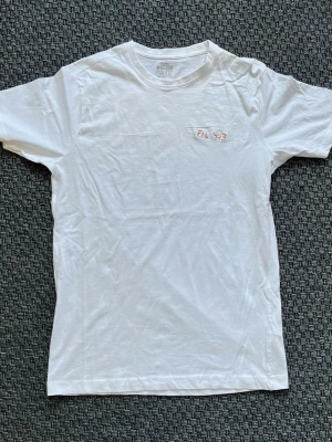 Handbroderad Vit t-shirt från Denim Project - Vit T-shirt med handbroderad text ”Fil 4:13”. ”Allt förmår jag i honom som ger mig kraft”. Texten är felplacerad (sne).