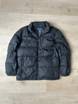 Svart Ralph Lauren Dunjacka Storlek S - Fin RL jacka i svart färg. Jackan är i mycket bra skick, tyvärr har en dragkedja till en ficka gått sönder - SE SISTA BILD men sparsamt använd. |  Äkta som allt annat jag säljer! ✅ |  Storlek: S (XL i barnstorlek) | Skick: Mycket Bra Skick  (SE SISTA BILD) | Färg: Svart | Märke: Ralph Lauren | Modell: Jacka |  Hör gärna av dig vid frågor så svarar jag så fort jag kan! 😁|   (SKU - 81)