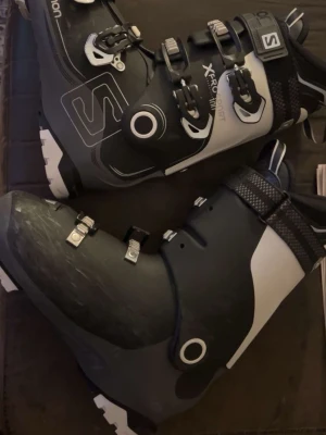 Salomon X Pro skidskor svart/vit - Säljer ett par Salomon X Pro skidskor i svart och vitt med coola detaljer och robust design. Skorna har flera spännen för optimal passform och är tillverkade i slitstarkt syntetmaterial. Perfekta för dig som vill ha stil och funktion i skidbacken.