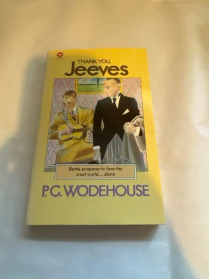 Thank You, Jeeves av P.G. Wodehouse - Rolig och klassisk roman med gul mjukpärm, titeln 'Thank You, Jeeves' och författaren P.G. Wodehouse på omslaget. Boken har ett färgglatt omslag med illustration av två män i eleganta kläder och texten 'Bertie prepares to face the cruel world...alone'.