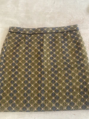 Mönstrad kortkjol i blått och grönt - Säljer en kortkjol med unikt geometriskt mönster i blått, grönt och beige. Kjolen har en rak passform och är tillverkad i ett tjockare tyg som ger struktur. Perfekt för dig som vill sticka ut med en cool retrostil.