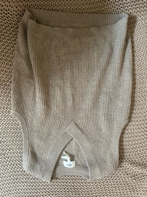 Beige ribbstickad väst från Object - Säljer en beige ribbstickad väst från Object med djup V-ringning och breda axelband. Västen har en mjuk och stretchig känsla, perfekt att bära över en skjorta eller t-shirt för en trendig lager-på-lager-look.