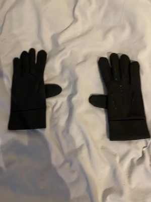 Svarta syntethandskar med grepp - Snygga svarta handskar i syntetmaterial med greppvänlig insida och diskreta detaljer på ovansidan. Perfekta för kyliga dagar och våren och när du vill ha både stil och funktion. Passar till det mesta och är lätta att matcha. Har jätte skön foder inuti 