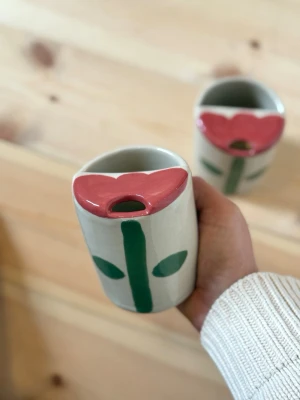 Handgjord keramikmugg med blomdekor - Take away-mugg i keramik – handgjord  Handgjord take away-mugg i keramik. Perfekt som återanvändbar kaffemugg på språng eller som en fin detalj i köket.   Rymmer ca 290 ml.  Varje mugg är tillverkad för hand, vilket innebär att små variationer och naturliga ojämnheter kan förekomma – det är en del av hantverket och gör varje exemplar helt unikt.  Rekommenderas att handdiskas. Tål diskmaskin och Micro.   Handmade – fruitnclay