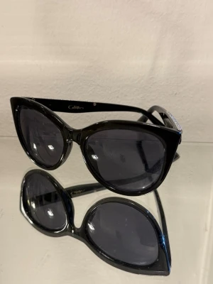 Svarta cat eye-solglasögon från Glitter - Solglasögon från glitter! Skit snygga på med en Cateye formad modell, som är i super fint skick!