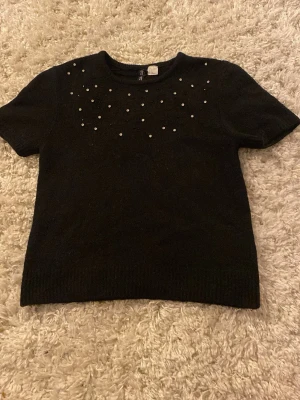 Svart stickad topp med pärlor H&M - Svart stickad topp från H&M. Toppen har korta ärmar och är dekorerad med små pärlor och paljetter framtill. Står storlek S fast skulle säga att den passar som en XXS🖤