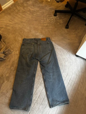 Blå raka Levi's jeans - Säljer ett par klassiska blå Levi's jeans med rak passform och fem fickor. Inte använd så mycket vilket syns på skicket. Hade sagt att dessa byxor är mer åt relaxed fit hållet än regular. STORLEK W32 L30