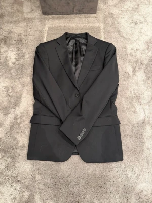 Svart klassisk kavaj från Dressmann - Stilren svart kavaj från Dressmann. Använd endast en gång därav mycket gott skick!