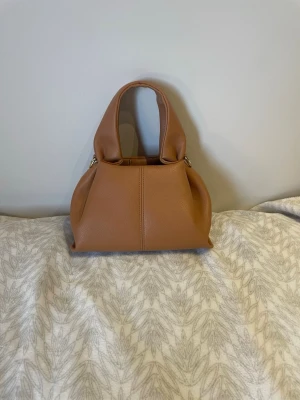 Väska - Jättesöt nästan oanvänd väska med måtten 24cm(bredd)x12cm(längd)x27cm(höjd). Kommer med ett längre band också