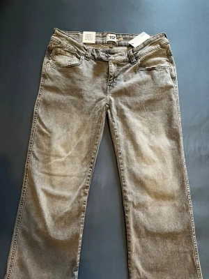 Grå raka jeans med broderade fickor - Säljer ett par helt oanvända grå jeans från Lager 157 med utsvängda ben och snygga detaljer . Jeansen har broderade mönster på bakfickorna. Jag säljer dessa jeans eftersom jag har glömt att ta på mig dom + jag har tappat vikt så dom är för stora nu.