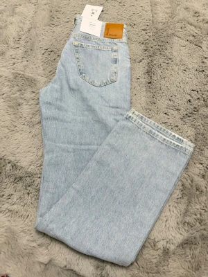 Ljusblå raka jeans från New Yorker - Säljer ett par ljusblå jeans med rak passform och låg midja. Jeansen har klassisk femficksdesign och är tillverkade i denim. Perfekta för en avslappnad och trendig look.