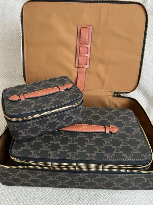 Celin resväskset sminkväskset i monogram canvas - Säljer ett exklusivt set med tre resväskor  i mörkbrun monogram canvas med ljusbruna läderhandtag och guldfärgade dragkedjor. Väskorna har rektangulär form och stilren design med  Paris-logga på handtagen. Perfekt för att resa med stil.