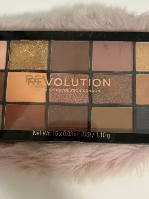 Ögonskuggspalett från Revolution - Använd 2 gånger.Säljer en ögonskuggspalett från Makeup Revolution med 15 olika nyanser i varma toner som guld, brunt, nude och koppar. Paletten innehåller både matta och skimrande skuggor i rektangulära pans, perfekt för kreativa sminkningar.