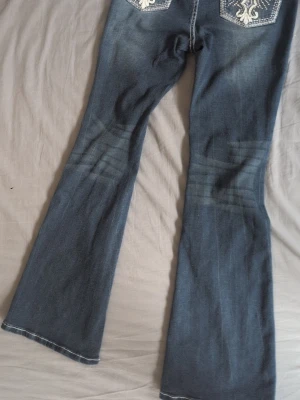 Blå bootcut jeans med broderi - Säljer ett par blå bootcut jeans, vita kontrastsömmar. Baksidan har broderade detaljer på fickorna som ger extra stil. Jeansen har klassisk femficksmodell. Aldrig använda och jag vet inte var de är ifrån eftersom jag fick de men de passa inte så därför valde jag att sälja de. (lapparna va klippta btw) Undrar ni något är det bara att skriva!❤️