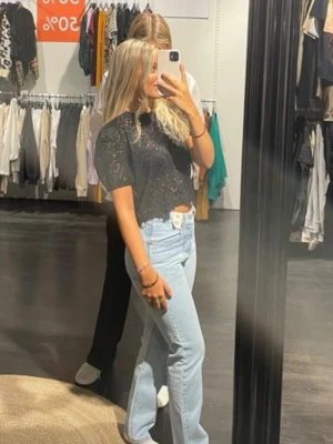 Svart spetsblus med blommönster - Säljer en svart blus med korta ärmar och vackert blommigt spetsmönster. Toppen har rund halsringning och är lätt croppad. 