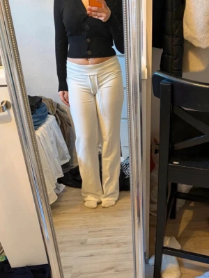 Svart cropped kofta med stora knappar - Snygg svart cropped kofta med djup v-ringning och fyra stora knappar framtill. Modellen är figurnära med långa ärmar och ribbade muddar. Perfekt att styla till höga byxor eller kjol för en trendig look.
