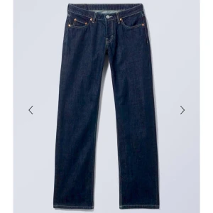 Arrow low jeans från Weekday - Säljer ett par mörkblå jeans från Weekday med rak passform och klassisk femficksdesign. Jeansen har hög midja och är tillverkade i kraftigt denimtyg med kontrastsömmar. Perfekta för en clean och stilren look.
