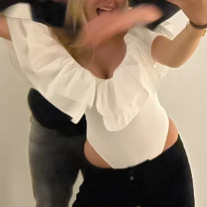 Vit volangbody ZARA - Säljer en vit blus med djup v-ringning och stora volangärmar. Toppen har en lös passform och är perfekt för dig som gillar en romantisk och trendig stil. Passar till både jeans och kjol för en snygg look.