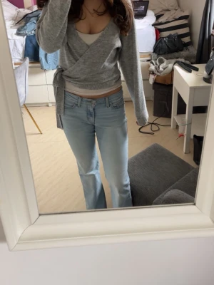 Grå omlottkofta från Even&Odd - Snygg grå omlott kofta från Even&Odd med v-ringning och knyt i sidan. Koftan har långärmade ärmar och ribbad nederkant, perfekt för att ge en chill och trendig vibe till din outfit. Köpt för 390kr. Säljs då den inte kommit till användning och är i väldigt bra skick.  Det är bara att skriva om de finns frågor💕